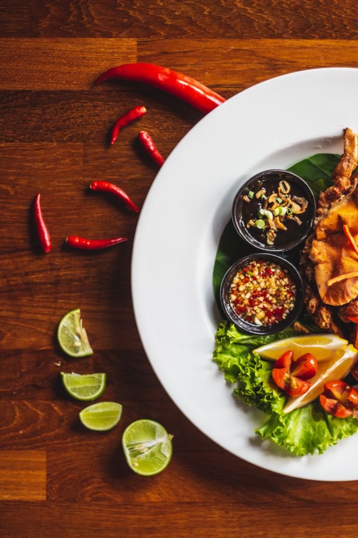 A colorful Thai meal featuring fresh ingredients like peppers and lime on a rustic table.