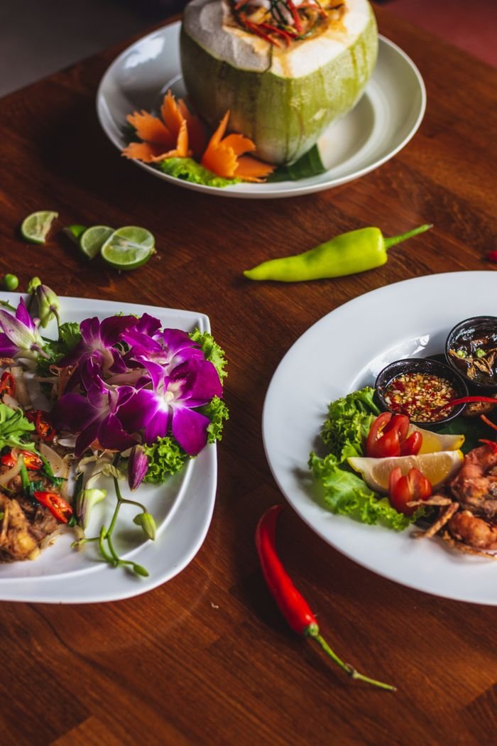 Beautifully plated Thai dishes with flowers and spices showcasing vibrant flavors.