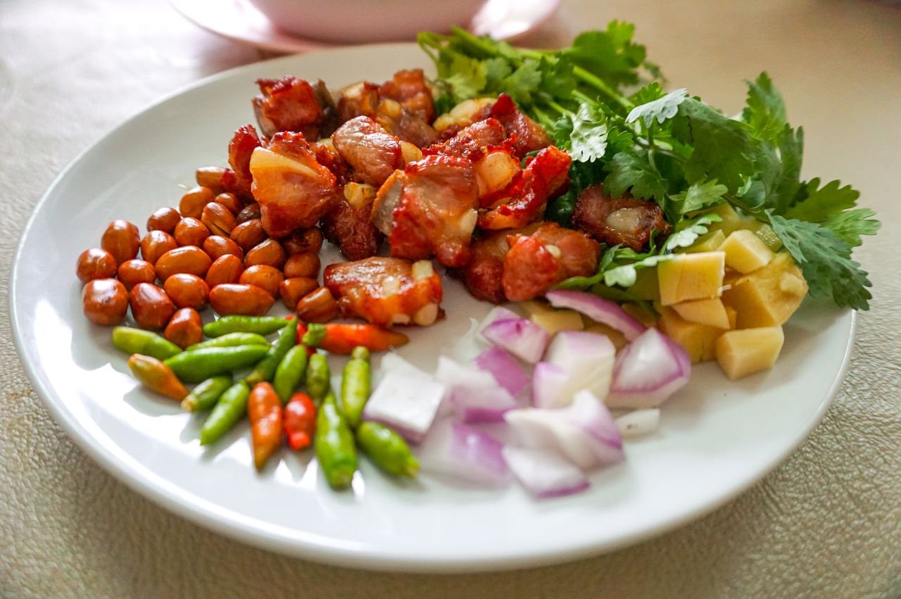Vibrant Asian appetizer on a plate featuring fresh vegetables, nuts, and marinated meat.