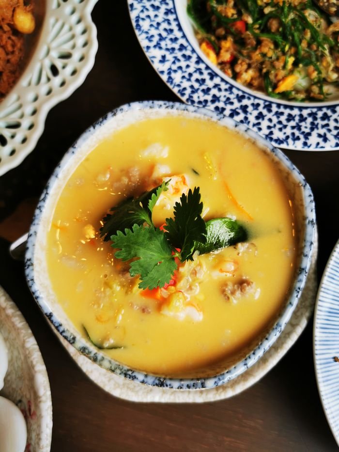 Top view of a delicious Thai curry soup garnished with cilantro in a traditional ceramic bowl.